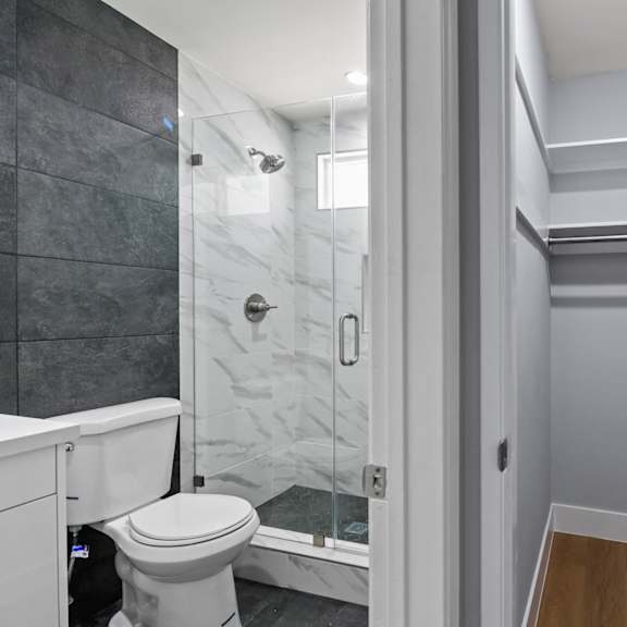 bathroom with walk-in shower and closet with shelving