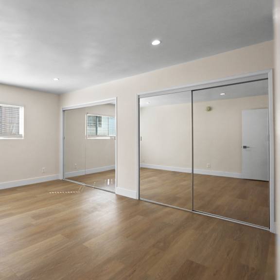 large bedroom with double mirrored closets and vinyl flooring