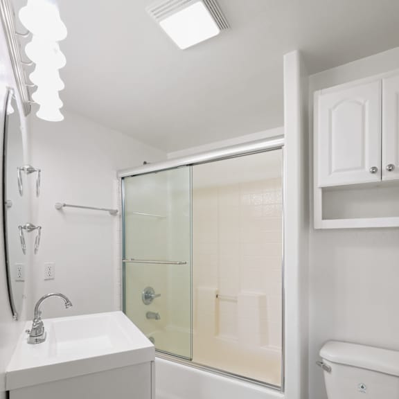 bathroom with bathtub with glass doors and additional storage cabinet