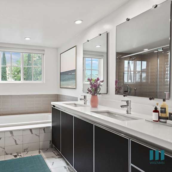 bathroom with bathtub, walk-in shower, and double-sink vanity with cabinet storage