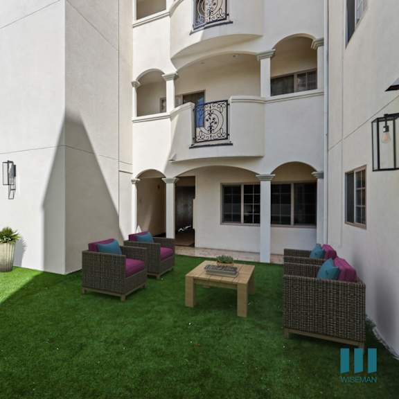 a courtyard with a lawn and chairs in front of a building