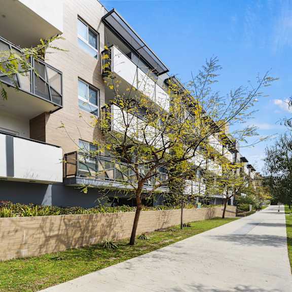 a modern apartment building with balconies and a sidewalk.