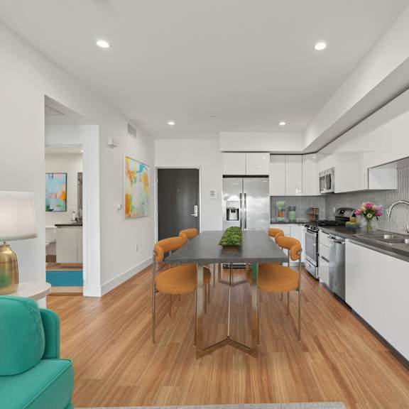 a modern kitchen with a green couch and a wooden table.