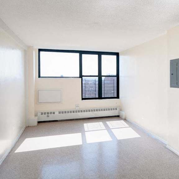 an empty room with a window and a radiator in it