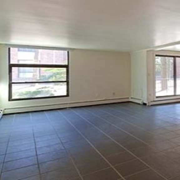 an empty living room with a tile floor and two windows