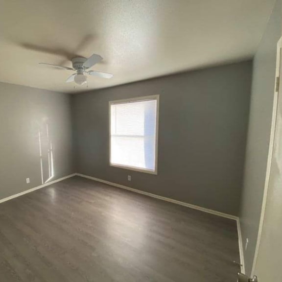 an empty room with a ceiling fan and a window