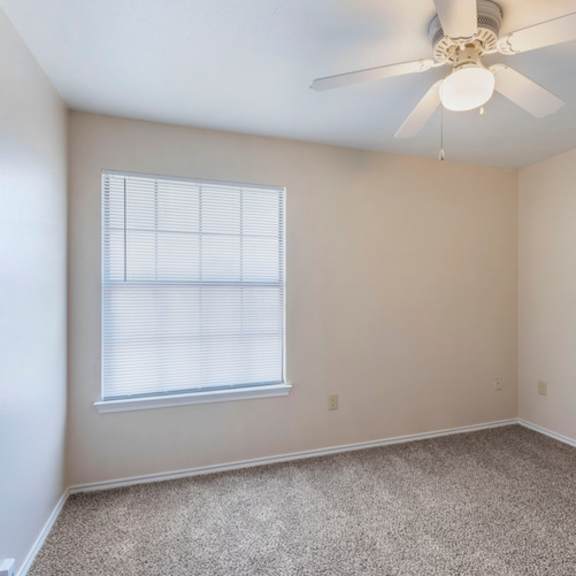 a room with a ceiling fan and carpeted floor.