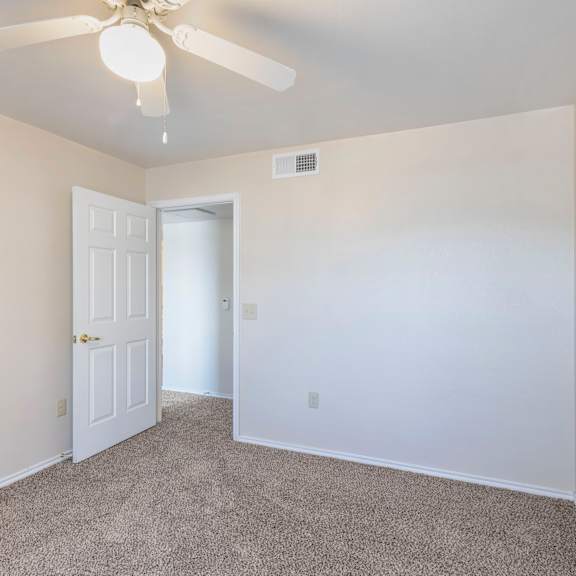 a room with a ceiling fan and carpeted floor.