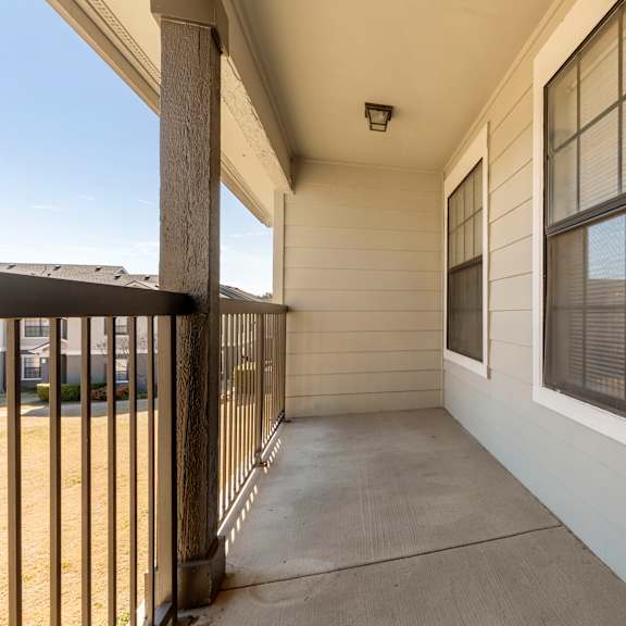 a balcony with a metal railing and a window with blinds.