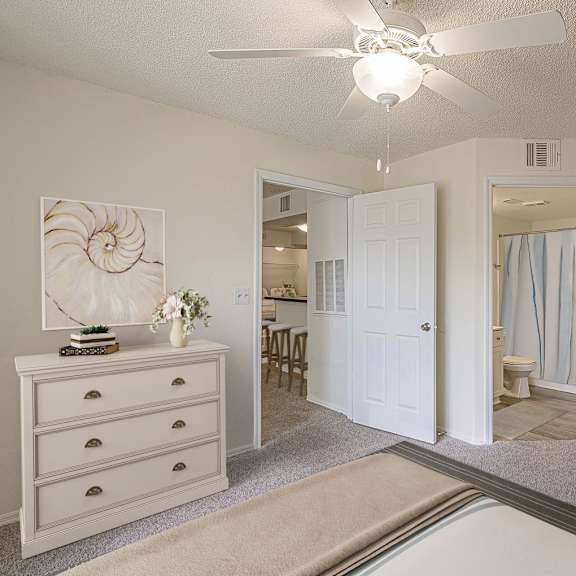 a white room with a dresser and a ceiling fan.