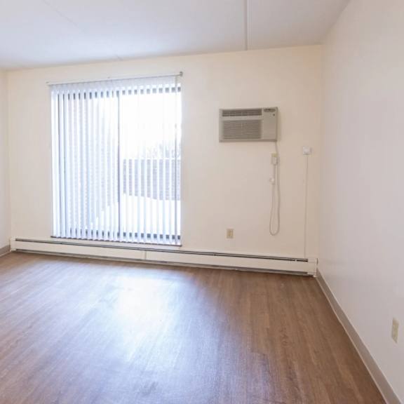 a room with wooden flooring and a window with blinds.