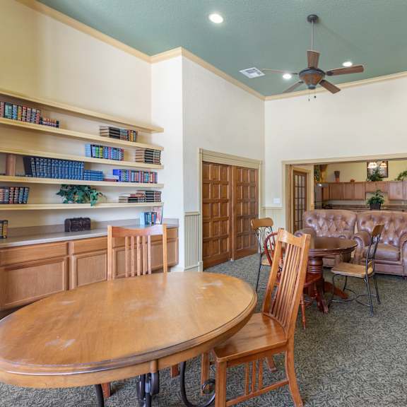 a room with a round wooden table surrounded by chairs.