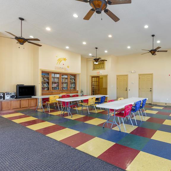 a room with tables and chairs and a ceiling fan.