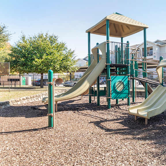 a playground with a green and tan slide and a brown and green play structure.