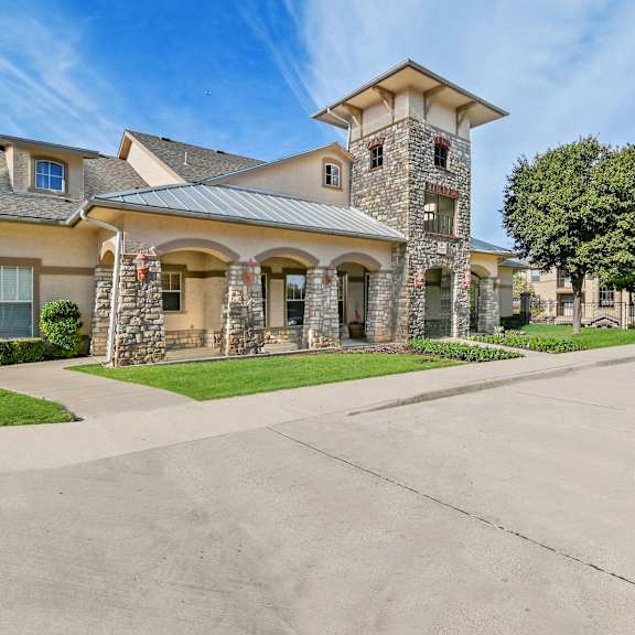 a large house with a stone tower and a driveway in front.
