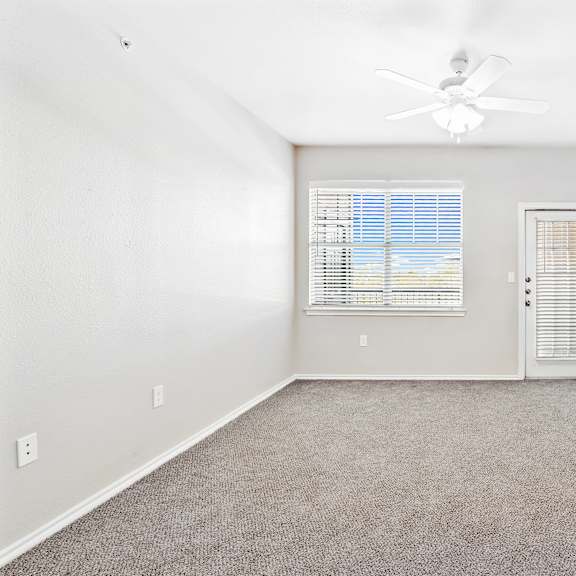 a room with a ceiling fan and a window with blinds.