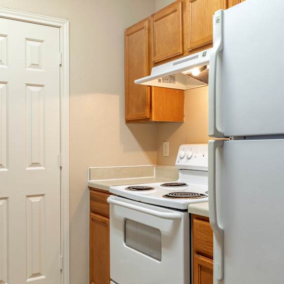 a white refrigerator stands in a kitchen next to a white door.