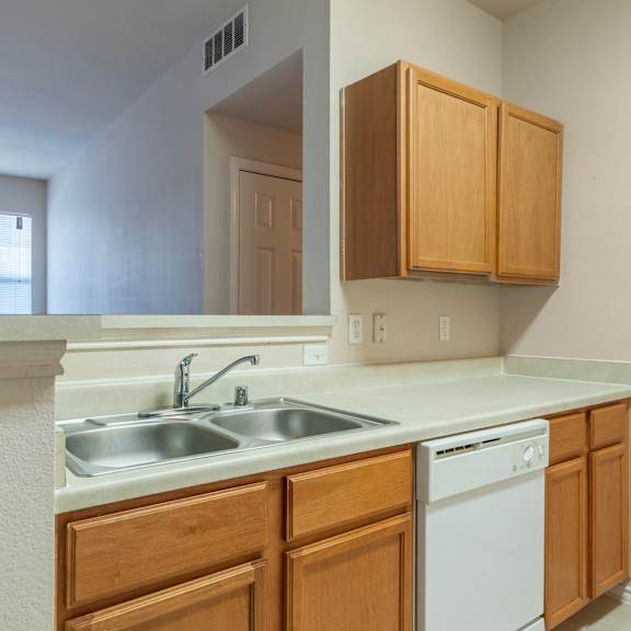 a kitchen with a white dishwasher and wooden cabinets.