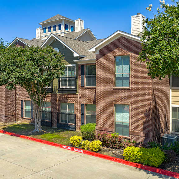 a red brick apartment building with a green tree in front.