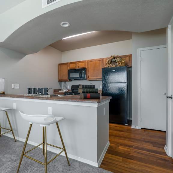 a kitchen with white countertops and gold bar stools.