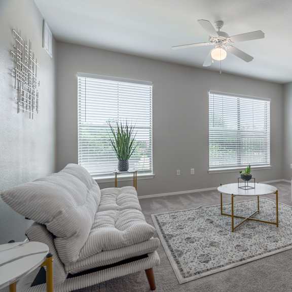 a living room with a white couch, a coffee table, and a ceiling fan.