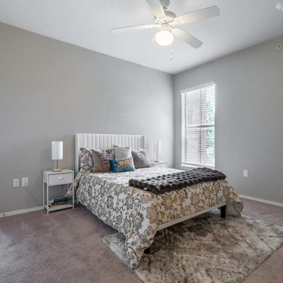 a bedroom with a bed, nightstand, and window.