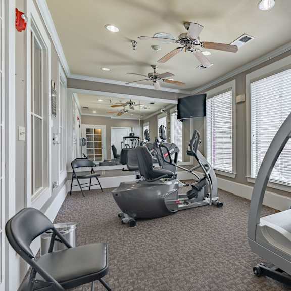 a home gym with a treadmill, exercise bike, and a television.