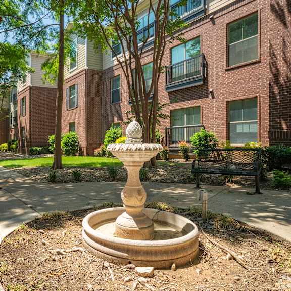 a garden with a fountain in the middle of a courtyard.