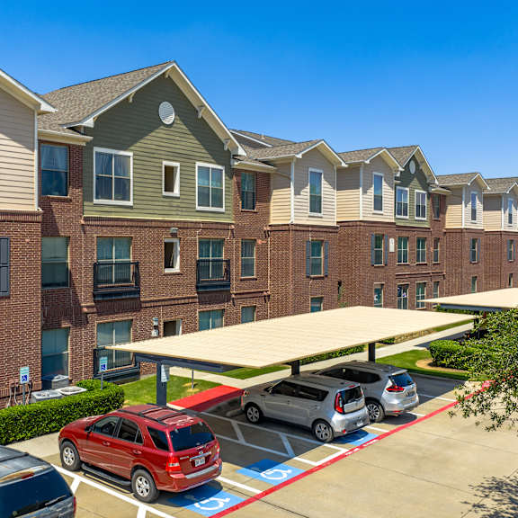 a row of apartment buildings with cars parked in front.