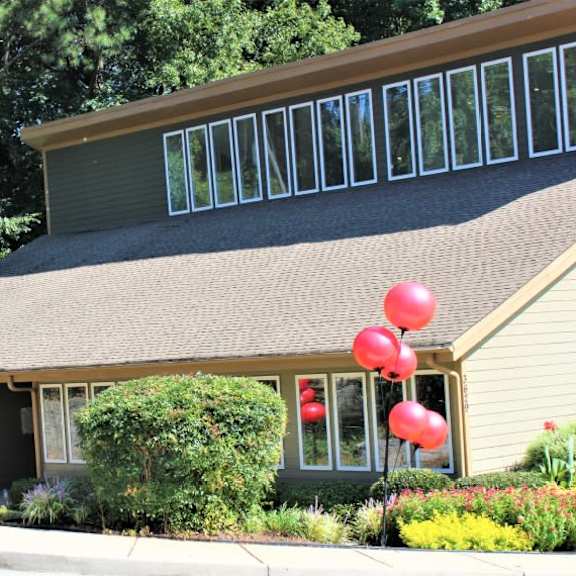 a house with a green lawn and a flag with red dots at clarkston station apartments, clarkston, 30021