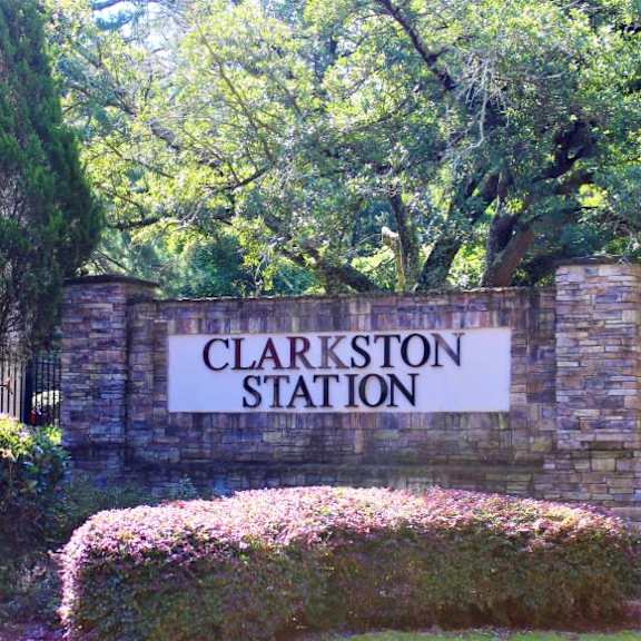 a sign that says clarkston station in front of a green hedge at clarkston station apartments, georgia