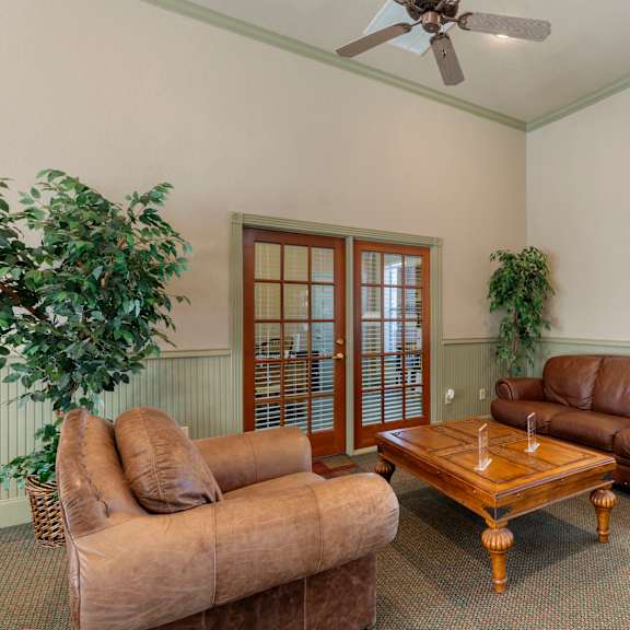 a living room with a brown couch, a wooden coffee table, and a ceiling fan.