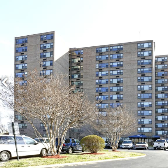 a parking lot in front of a large building with cars parked.
