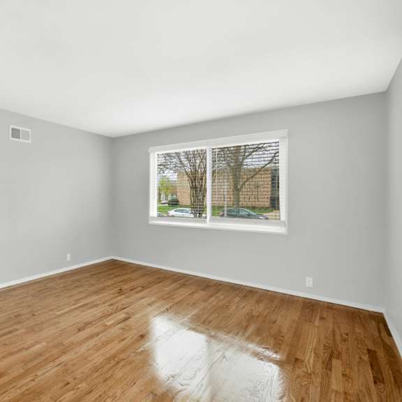 a bedroom with hardwood floors and a large window