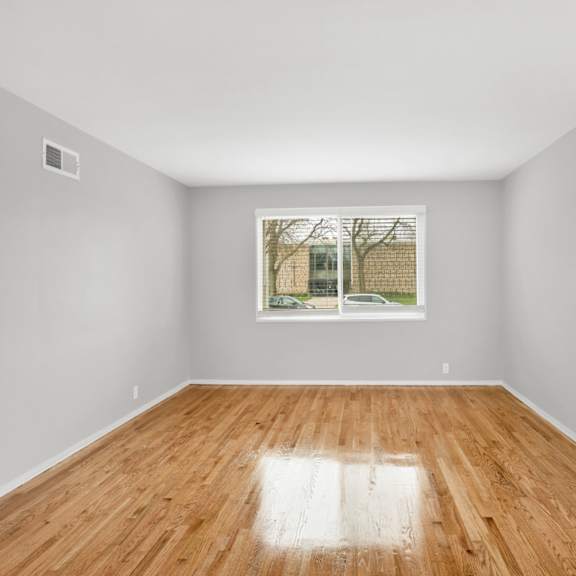 a bedroom with a large window and hardwood floors