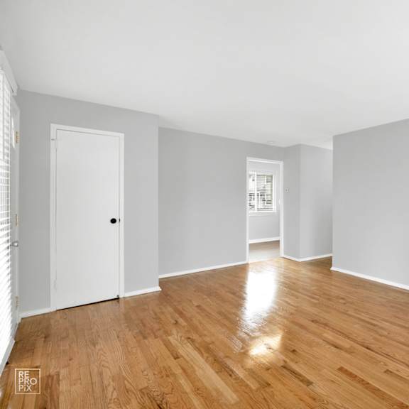 a bedroom with grey walls and a hardwood floor