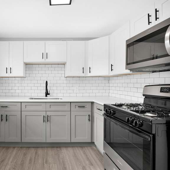 a kitchen with white cabinets and a black stove