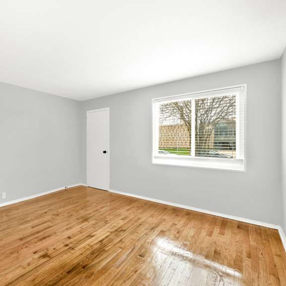 a bedroom with hardwood floors and a large window