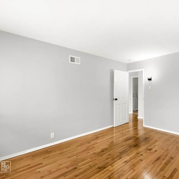 a bedroom with gray walls and hardwood floors