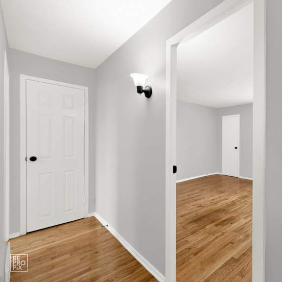 a bedroom with gray walls and a hardwood floor