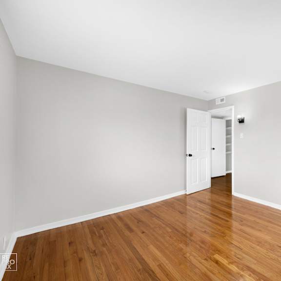 a bedroom with white walls and hardwood floors