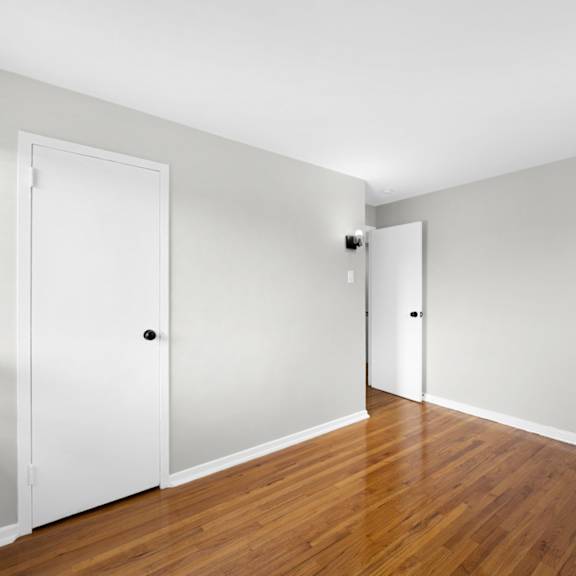 a bedroom with white walls and hardwood floors