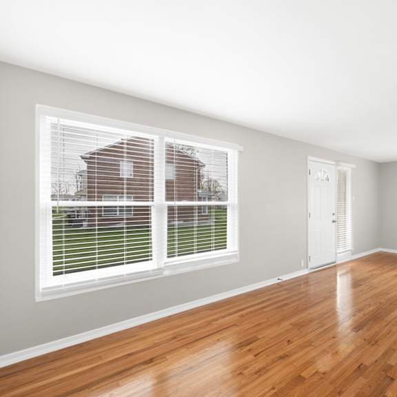 a bedroom with a large window and hardwood floors