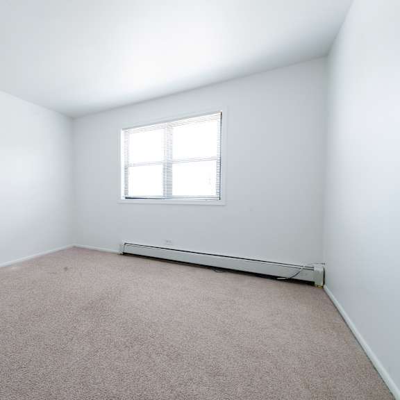 an empty room with white walls and a window