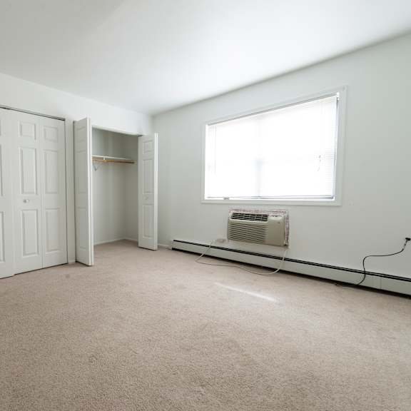 an empty room with two doors and a radiator and a window