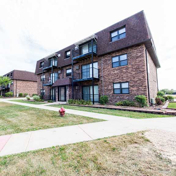 a brick apartment building with a red fire hydrant on the sidewalk