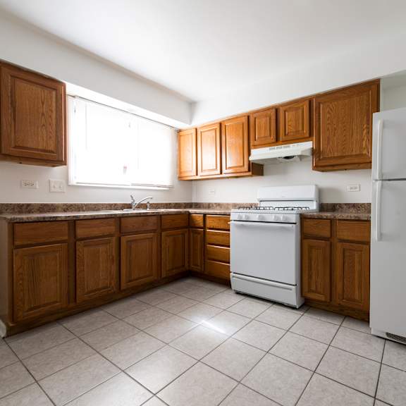 an empty kitchen with white appliances and wooden cabinets