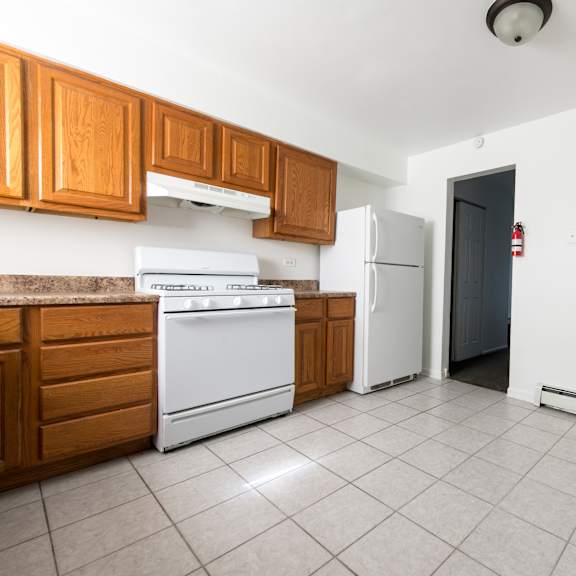 an empty kitchen with white appliances and wooden cabinets