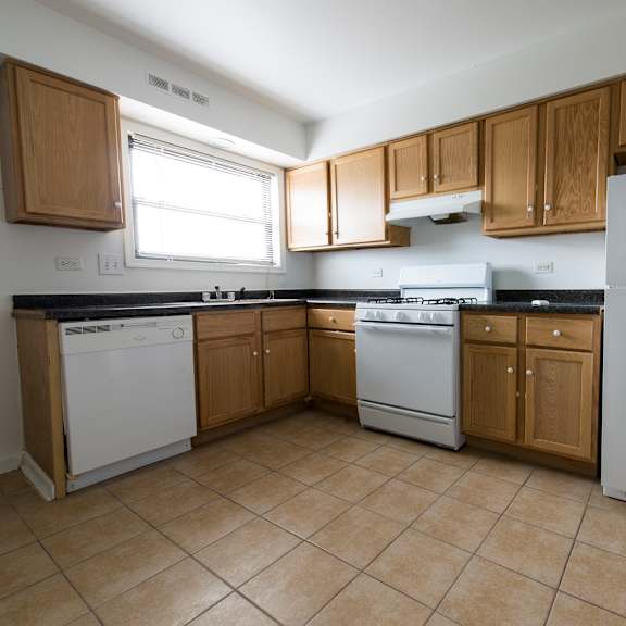 an empty kitchen with white appliances and wooden cabinets