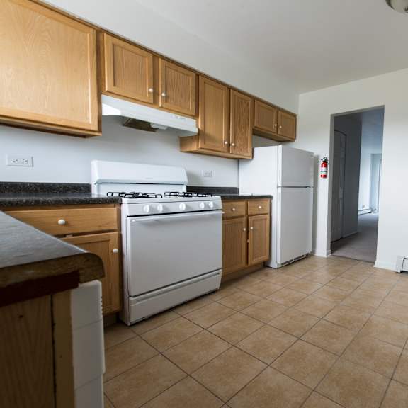 an empty kitchen with white appliances and wooden cabinets